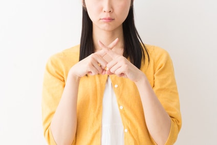 指でバツ印を作る女性