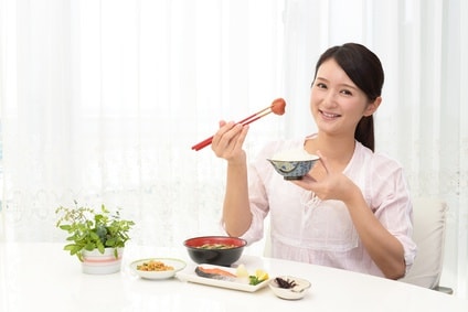箸で梅干しを持つ女性
