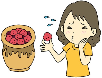 梅干しを食べて酸っぱい顔をする女性