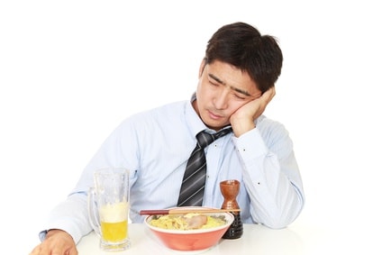 酔っぱらっているサラリーマンがラーメンを食べている
