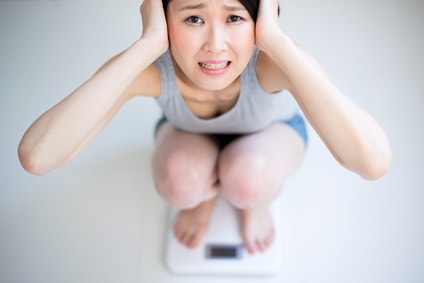 体重計で頭を抱える女性